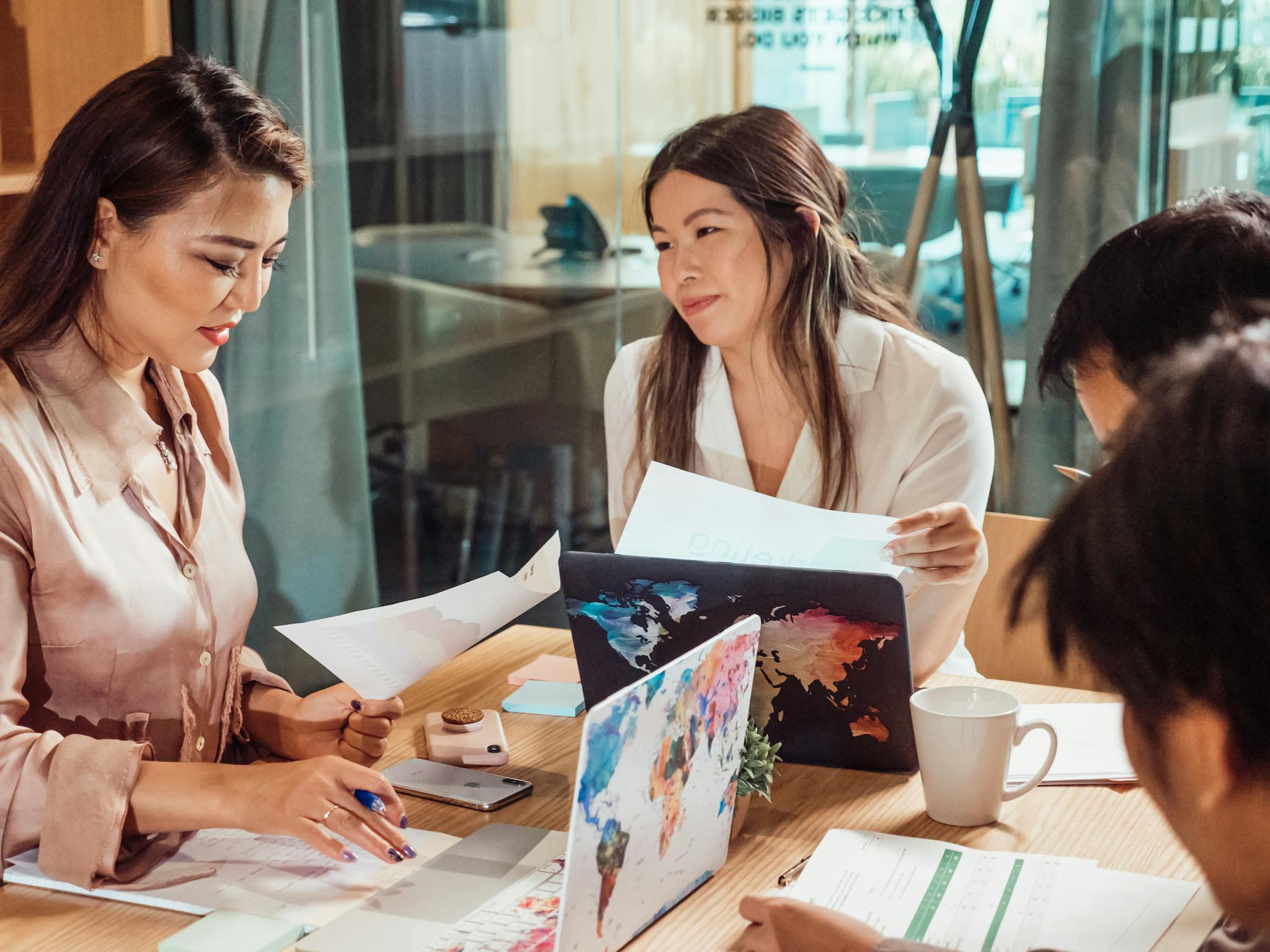 Group of Asian business professionals discussing plans in a modern office setting.
