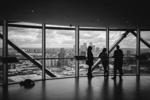 black and white image of business people standing by windows overlooking a skyline by Charles Forerunner